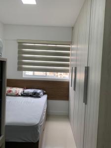 een kleine slaapkamer met een bed en een raam bij Apto aconchegante e elegante Morretes itapema in Meia Praia