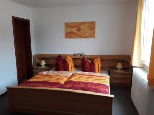 1 dormitorio con 1 cama con almohadas de color rojo y naranja en Haus Bergfried SORGENFREI BUCHEN en Wieda