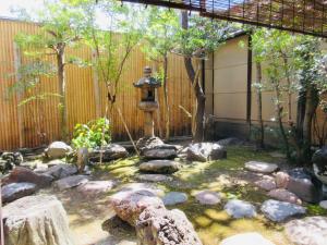 a garden with a fountain and rocks and a fence at Tansada Heritage Machiya in Kyoto