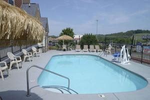 - une piscine sur une terrasse avec des chaises et des tables dans l'établissement Microtel Inn & Suites by Wyndham Pigeon Forge, à Pigeon Forge