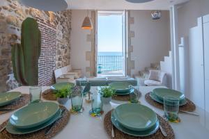 a dining room with a table with green plates on it at Veronique by Dimore in Sicily in Siracusa