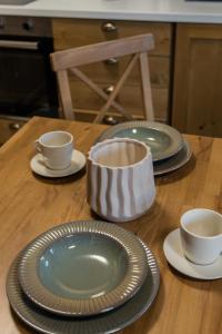 una mesa de madera con platos y tazas. en Pirin Golf and Spa Cozy Studio, en Bansko