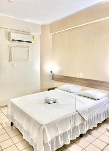 - une chambre avec un grand lit blanc et des draps blancs dans l'établissement Hotel Canto Da Praia, à São Luís