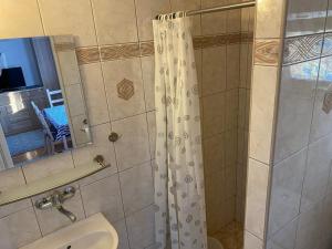 a bathroom with a shower with a sink and a mirror at Dom Gościnny Posejdon in Pobierowo