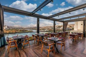 イスタンブールにあるRamada by Wyndham Istanbul Golden Hornのテーブルと椅子、大きな窓のあるレストラン