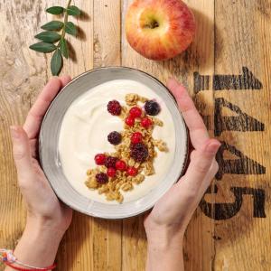 a person holding a bowl of cereal with fruit on a table at Eco Boutique Hostal Grau in Barcelona