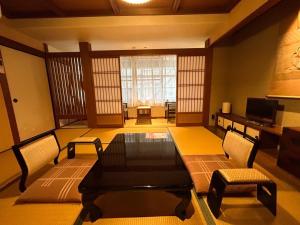 a room with a table and chairs and a television at Sangai Ryokan in Gotsu