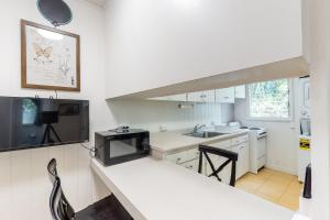 a white kitchen with a sink and a microwave at Monsarrat Apt D - 30-Night Minimum in Honolulu