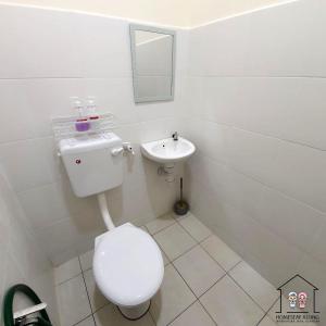 a white bathroom with a toilet and a sink at Homestay by NAF in Kuantan