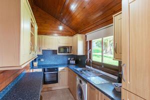 a kitchen with wooden cabinets and blue counter tops at Lady Galloway 28 with Hot Tub in Newton Stewart