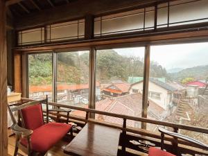 a room with a large window with chairs and a table at Sangai Ryokan in Gotsu