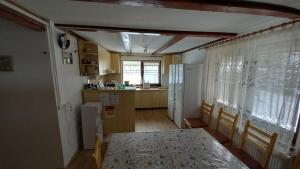 a room with a table and a kitchen with a window at Pensiunea turistica Adler in Bălceşti