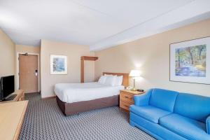 a hotel room with a bed and a blue couch at Travelodge by Wyndham Bridgewater in Bridgewater