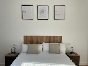 een slaapkamer met een wit bed met vier foto's aan de muur bij AZ El Balcón a la Basílica II - vistas inmejorables a la Basílica del Pilar! in Zaragoza