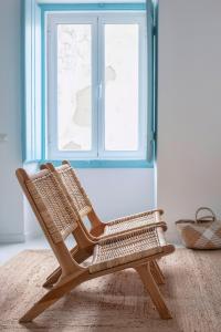 a wooden rocking chair sitting in front of a window at Casa Azul do Olival in Alcácer do Sal