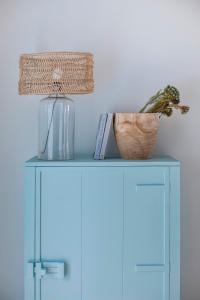 a blue cabinet with a plant and a lamp on it at Casa Azul do Olival in Alcácer do Sal