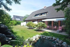 een huis met een vijver in de tuin bij Biberhues-EG in Archsum