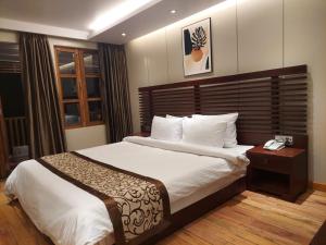 a bedroom with a large bed with a wooden headboard at D' more Sajek Valley Hotel & Resort in Māhmuam