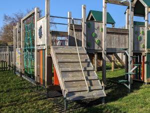 a set of wooden play structures with a slide at Modern 2 Bedroom Mobile home with parking on St Helens Coastal Resort Isle of Wight in Saint Helens