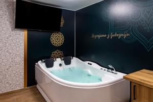 a bath tub in a bathroom with a sign on the wall at Vila Marin in Prevalje