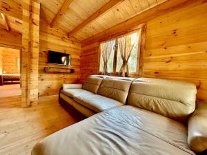 a living room with a couch in a log cabin at Chalet bois jacuzzi in Bessan