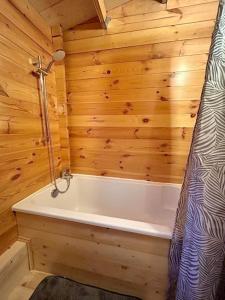 a bathroom with a bath tub in a wooden cabin at Chalet bois jacuzzi in Bessan