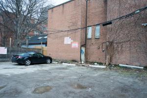 a car parked in a parking lot next to a brick building at Guests House in Toronto