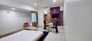 a room with a bed and a table and a tv at Hotel Easy Retreat in Vapi