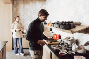 Hotel Lisl - Alpine Comfort في كوهتاي: رجل وامرأة يقفان في مطبخ يجهزان الطعام