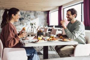 Um homem e uma mulher sentados à mesa a comer. em Hotel Lisl - Alpine Comfort em Kühtai