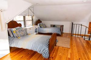 two beds in a room with wooden floors at HOT TUB Charming & Chic Mountain Gem On Sleepy Creek in Berkeley Springs