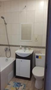 a bathroom with a toilet and a sink and a bath tub at Green Park Domina apartment in Rīga