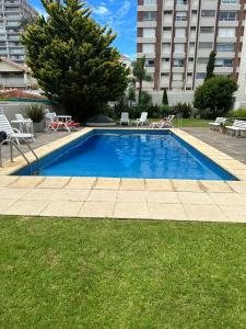 a woman laying on a lawn next to a swimming pool at El Remanso - Suite 104 in Punta del Este