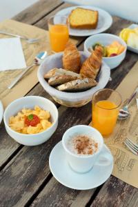 a wooden table with plates of breakfast foods and orange juice at Aldeia da Pedralva - Slow Village in Vila do Bispo