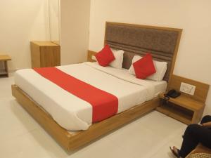 a bedroom with a large bed with red pillows at Hotel Maan Palace in Ahmedabad