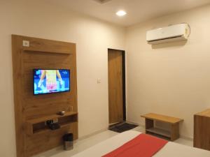 a room with a bed and a television on a wall at Hotel Maan Palace in Ahmedabad