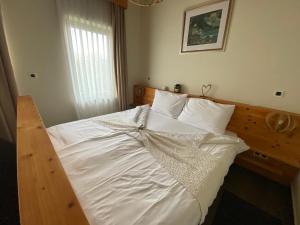 1 dormitorio con 1 cama con sábanas y almohadas blancas en Zagreb Camp Bungalows, en Rakitje