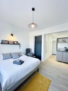 1 Schlafzimmer mit einem großen weißen Bett und einer Küche in der Unterkunft LE PARADIS FISCAL, 5min Bâle, parking privé in Saint-Louis
