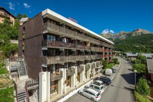 een gebouw waar auto's voor geparkeerd staan bij Hotel Plein Soleil in Allos