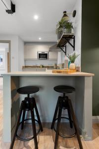 a kitchen with two bar stools at a counter at Luxe Courtyard Apartment for 4 Near Exeter City Centre in Exeter