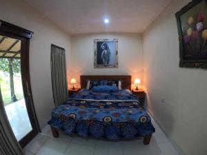 1 dormitorio con 1 cama, 2 lámparas y ventana en Honey Home Stay en Canggu