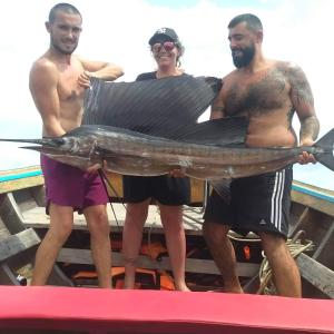 a group of three men holding a fish on a boat at P P Garden Home Bungalow in Phi Phi Islands