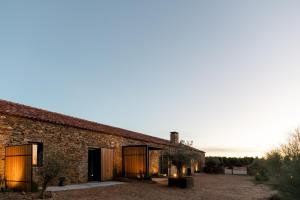 an old brick building with a sunset in the background at Herdade dos Abegões in Salvaterra do Extremo