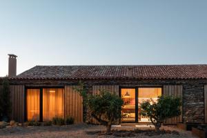 a stone house with glass doors and windows at Herdade dos Abegões in Salvaterra do Extremo