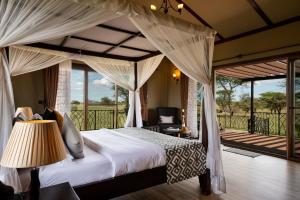 a bedroom with a canopy bed and a balcony at Serengeti Sametu Camp in Serengeti National Park
