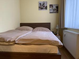 Una cama con sábanas blancas y almohadas en un dormitorio en Penzion Park - 2 izbové apartmány, en Nové Mesto nad Váhom