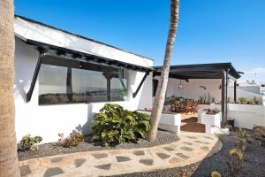 a white house with a palm tree and a patio at Casa Los Angeles in Tías