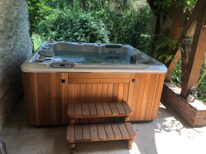 Un jacuzzi sentado en un patio con un banco. en La Rozeliere, en Rozoy-le-Vieil