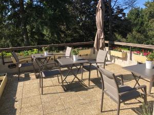 Un patio con mesas y sillas y una sombrilla. en La Rozeliere, en Rozoy-le-Vieil