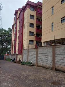 un edificio alto junto a una calle de ladrillo con un edificio en Cozy Apartment en Ruaka